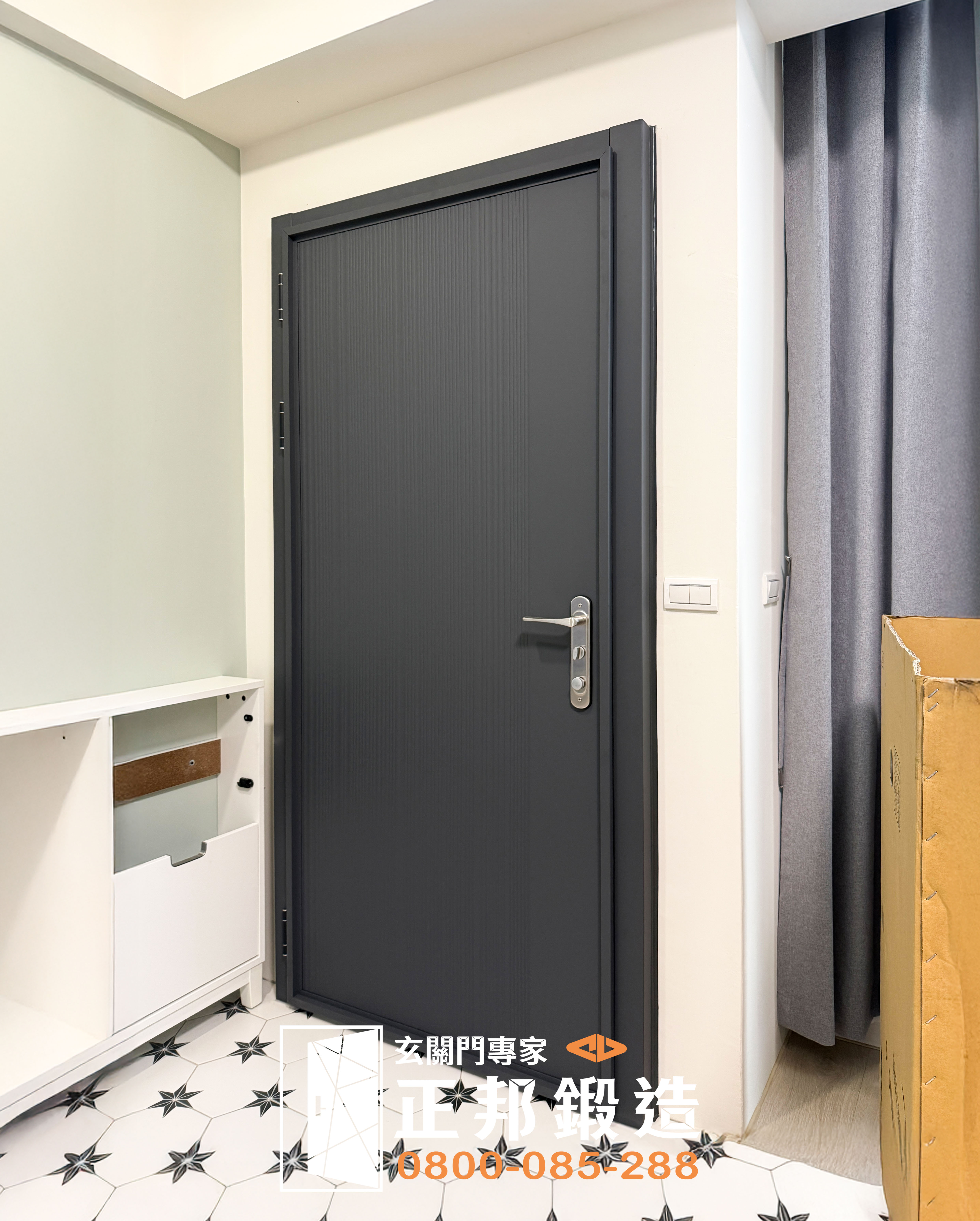 新竹住家換門完成後的室內斜角實景，C9B-2058深灰消光玄關門與白色牆面、灰色窗簾及室內磁磚形成沉穩對比，可清楚看到新門安裝後的整體比例與住宅玄關空間搭配效果。
