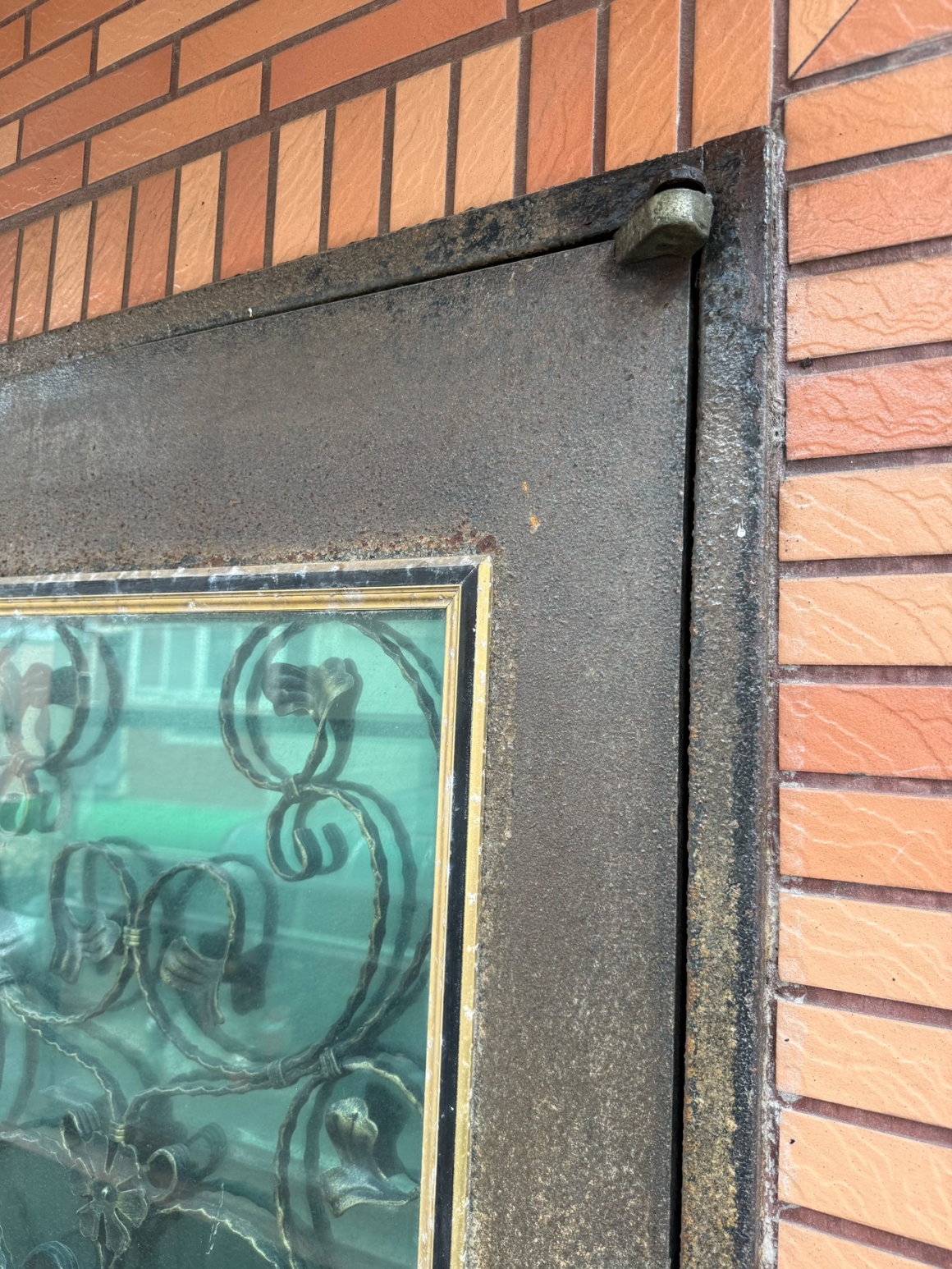 桃園新屋玄關大門生鏽實際現勘照片，可看到舊門門框與門扇接合位置已有明顯鏽蝕與表面劣化，這類鏽蝕若深入金屬結構，處理時不能只從外觀重新補漆判斷。