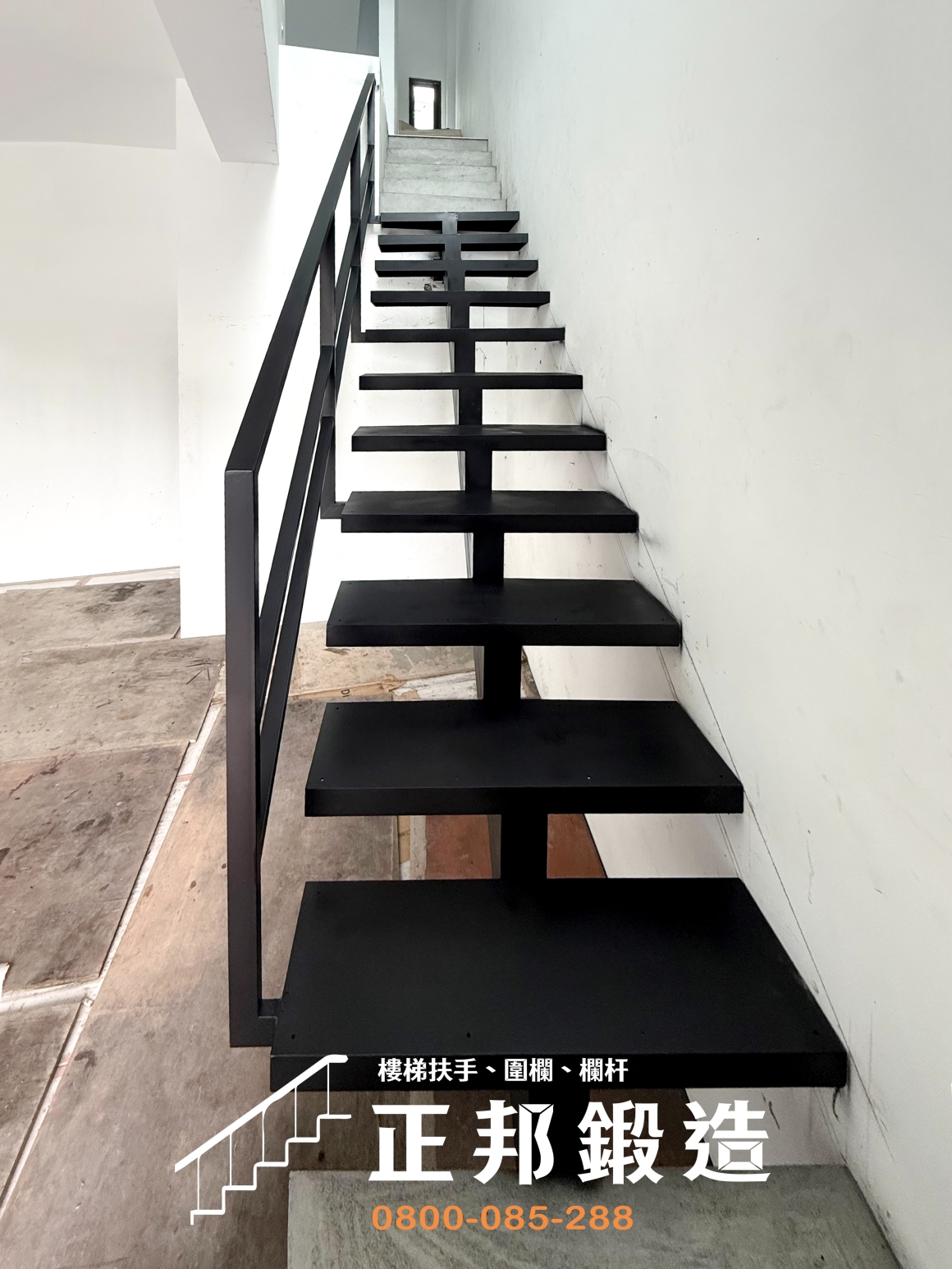 正邦鍛造南投住宅一至二樓龍骨梯完工實景，黑色消光鋼構沿白色牆面斜向上升，中央主骨架支撐一階階向兩側延伸的踏板，外側搭配簡潔的黑色鐵件扶手與橫向欄杆。樓梯下方沒有封閉式梯體，保留可視通透的開放空間，呈現客製鐵樓梯的輕盈視覺。