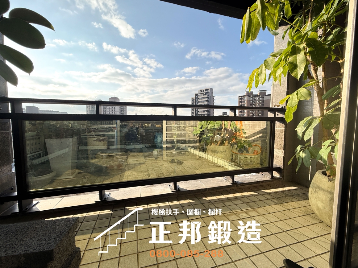 台北市松隆路正邦鍛造不鏽鋼玻璃欄杆完工照片，從陽台側面觀察9637黑消光金屬框架、水平上橫桿、玻璃面板與下方支撐固定位置。C9F-1015欄杆搭配10mm綠半反射強化玻璃，讓陽台維持採光與視野，同時透過重新製作骨架處理原有欄杆老化更換需求。
