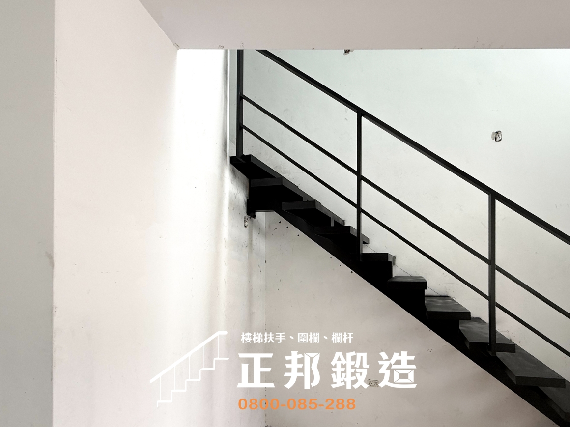 正邦鍛造南投龍骨梯完工側視角度，黑色消光扶手沿梯段斜線配置，搭配細直立柱與橫向欄杆，形成俐落的幾何線條。踏板依序向上銜接既有上層混凝土階梯，黑色鋼構與白色牆面對比鮮明，可作為住宅鐵樓梯扶手造型與空間視覺規劃的實際參考。